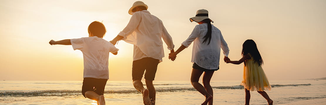Happy Asian family at the beach during sunset.